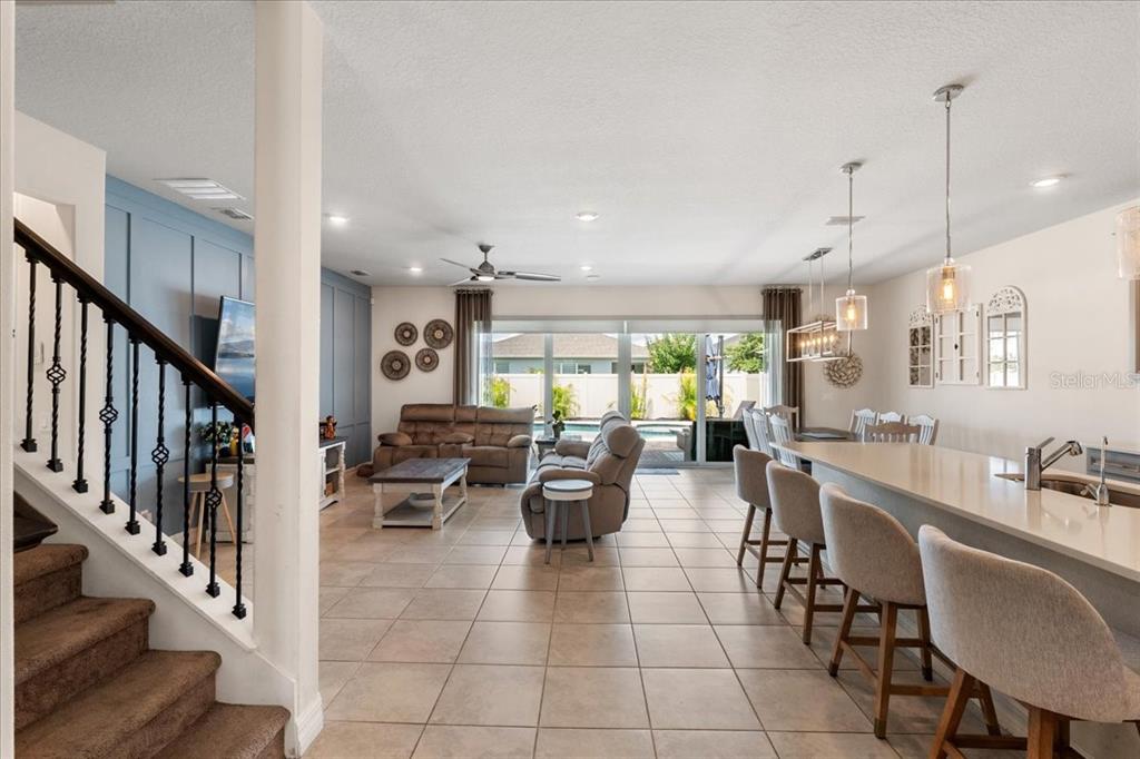 An open-concept living and dining area features tile flooring, a kitchen island, and sliding doors — 2712 TIMBERGROVE STREET, ST CLOUD, FL
