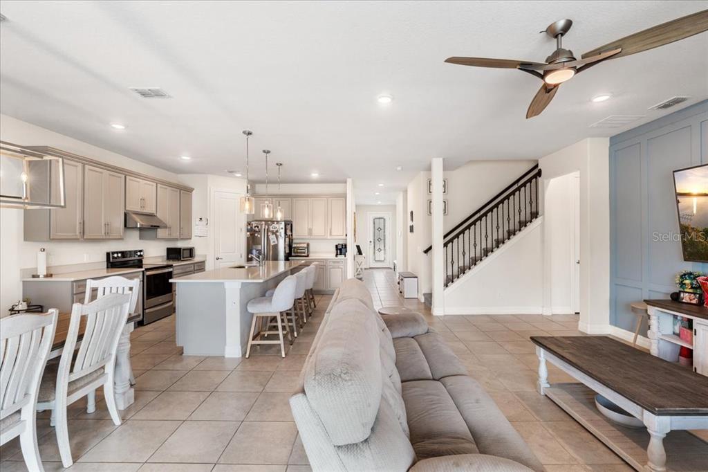 An open-concept kitchen and living area features light cabinetry, a central island, and a staircase — 2712 TIMBERGROVE STREET, ST CLOUD, FL