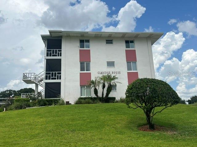 A three-story white apartment building with red accents stands on a grassy hill — 1700 6TH STREET NW UNIT C21, WINTER HAVEN, FL