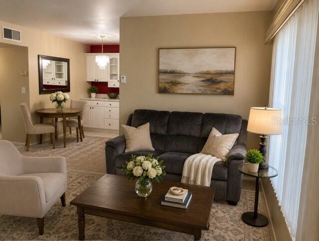 A living room features a dark gray sofa, a wooden coffee table, and an adjacent dining area — 1700 6TH STREET NW UNIT C21, WINTER HAVEN, FL