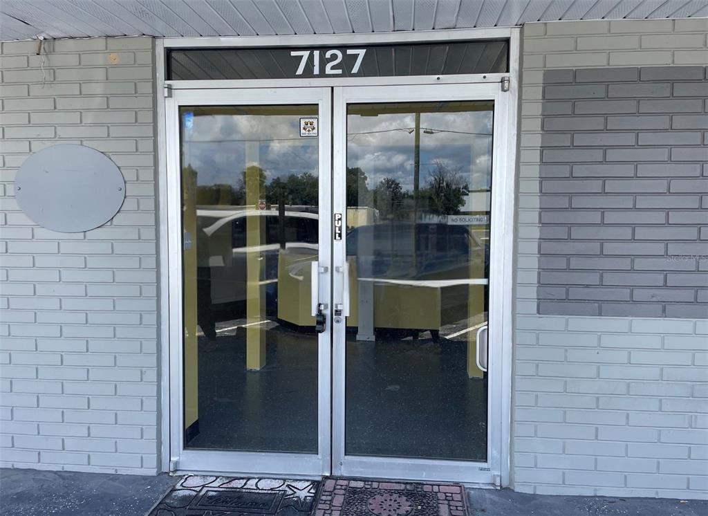 A glass double door entrance with a brick exterior and the number 7127 above — 7127 US HIGHWAY 19, NEW PORT RICHEY, FL