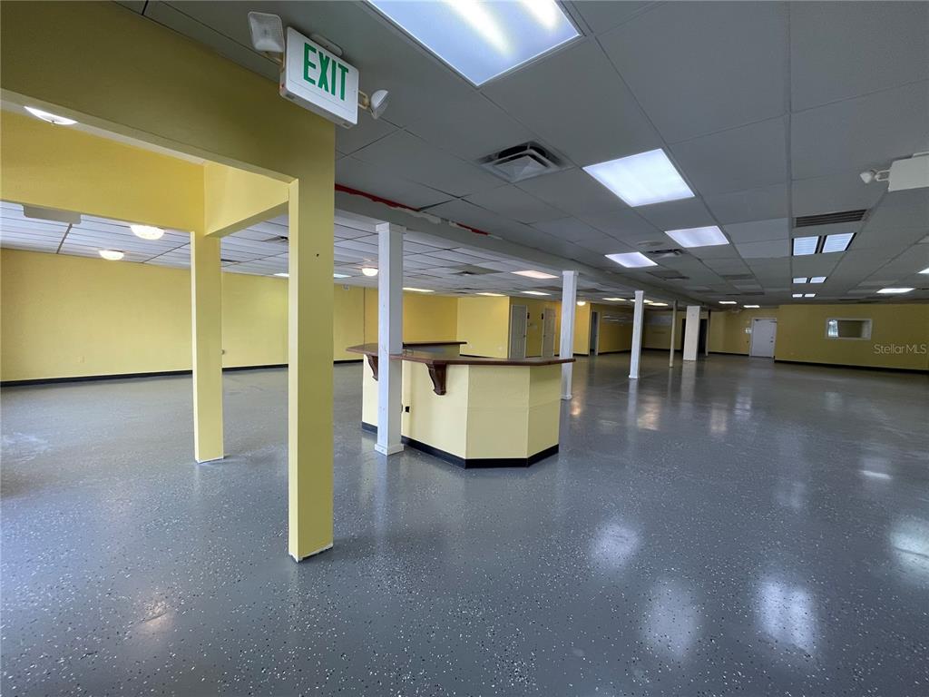 An open commercial space features yellow walls, a central service counter, and gray speckled flooring — 7127 US HIGHWAY 19, NEW PORT RICHEY, FL