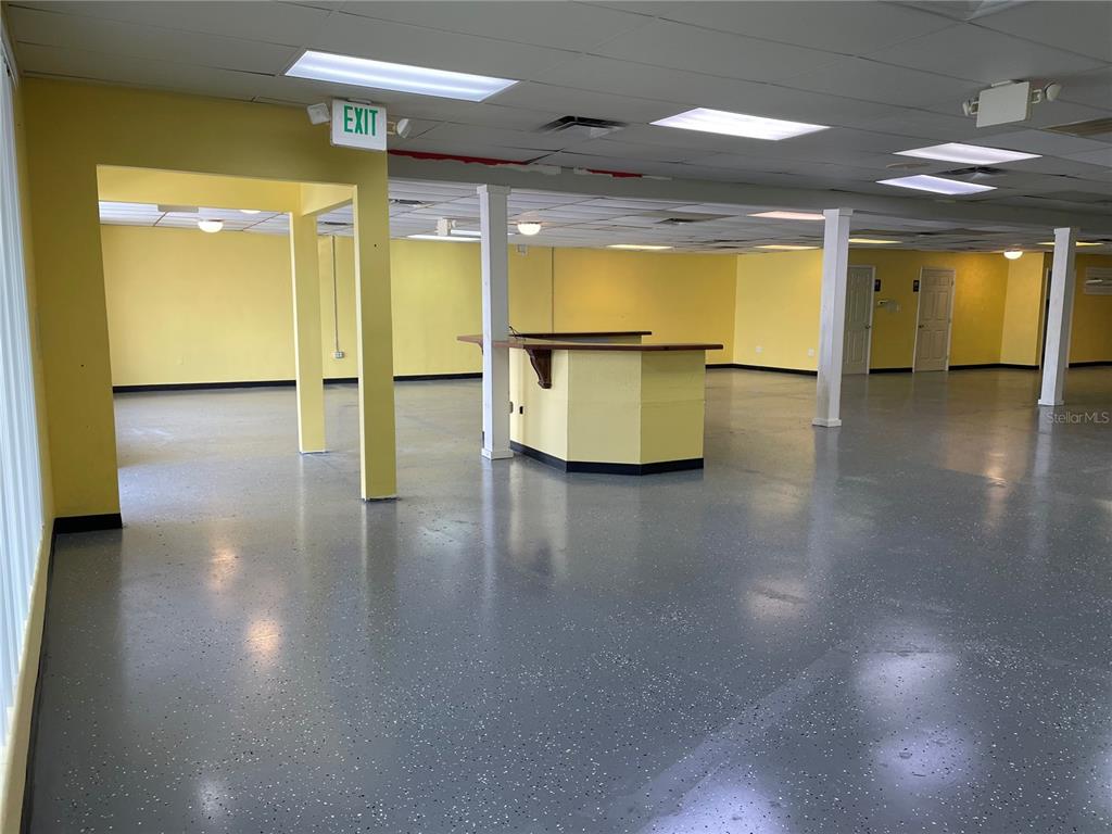 An open commercial space features yellow walls, a central service counter, and gray speckled flooring — 7127 US HIGHWAY 19, NEW PORT RICHEY, FL