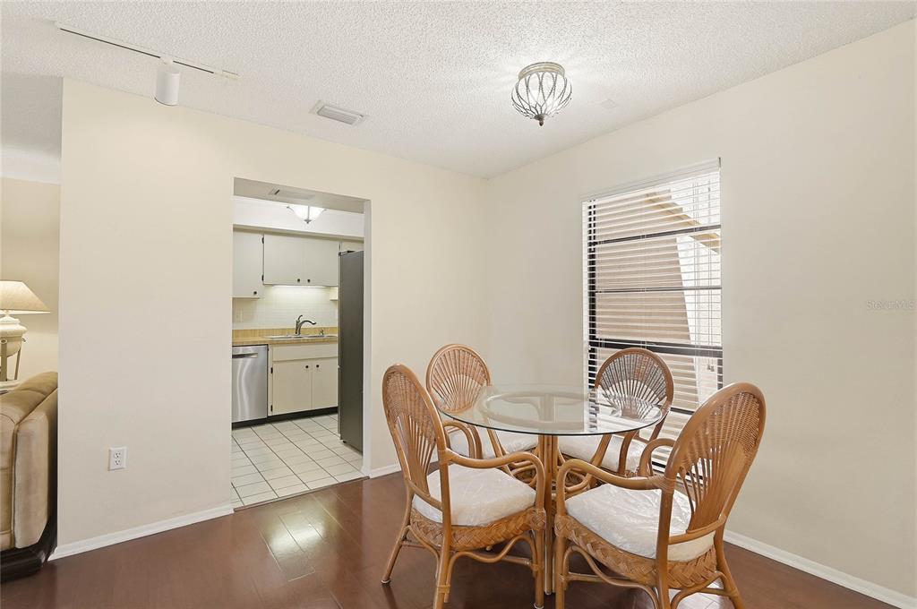 A dining area with a glass table and wicker chairs leads into a tiled kitchen — 3189 GLEN ELYN BOULEVARD UNIT 3, SARASOTA, FL
