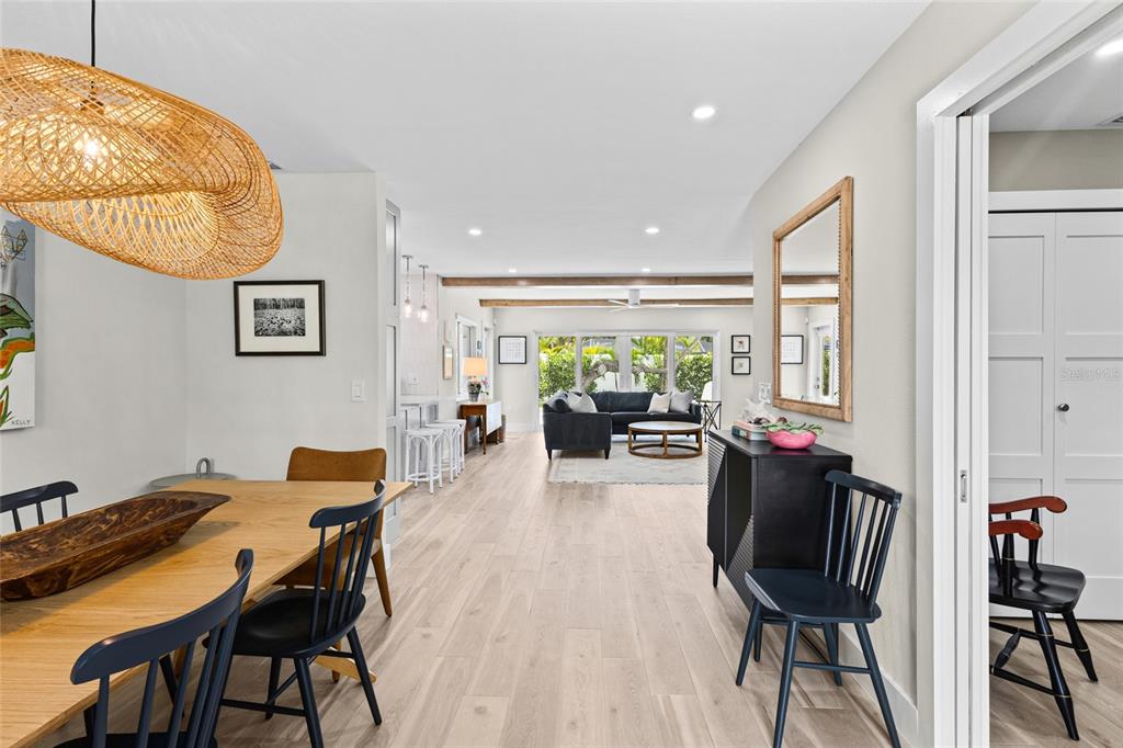 A dining area leads into a living room with light wood floors and white walls — 801 EDGEMERE LANE, SARASOTA, FL