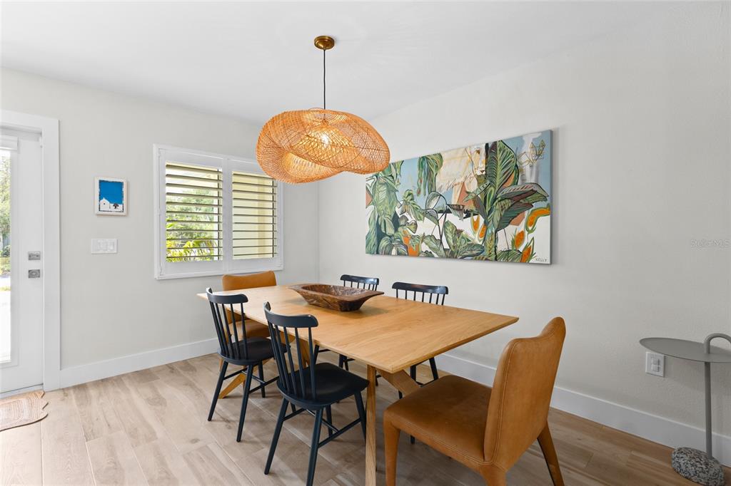 A dining room features a wooden table, mixed seating, a woven pendant light, and wall art — 801 EDGEMERE LANE, SARASOTA, FL