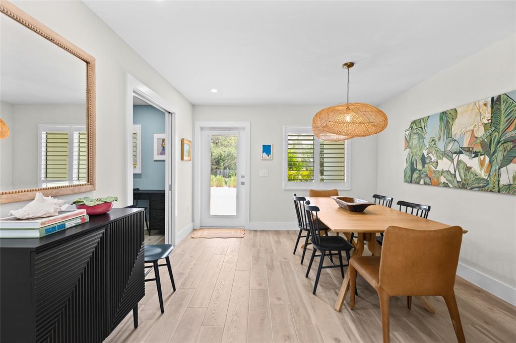 A dining room features a wooden table, black chairs, a woven pendant light, and wood flooring — 801 EDGEMERE LANE, SARASOTA, FL