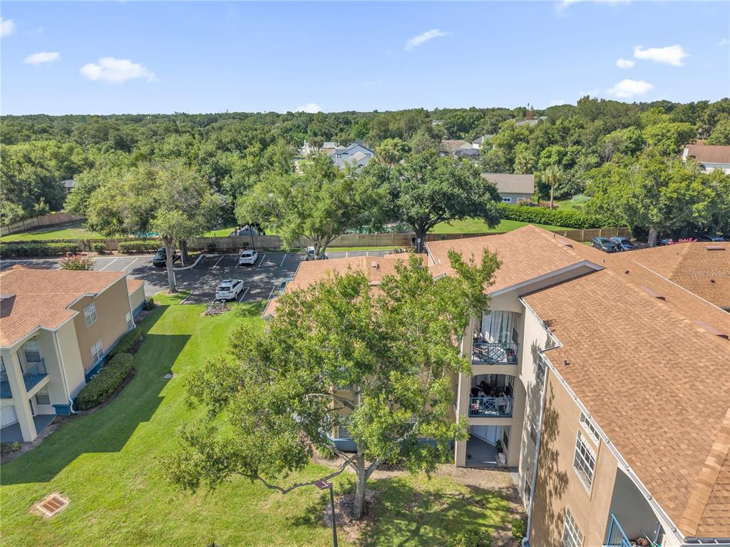 An aerial view shows apartment buildings with brown roofs, balconies, and surrounding trees and parking — 7300 WESTPOINTE BOULEVARD UNIT 717, ORLANDO, FL