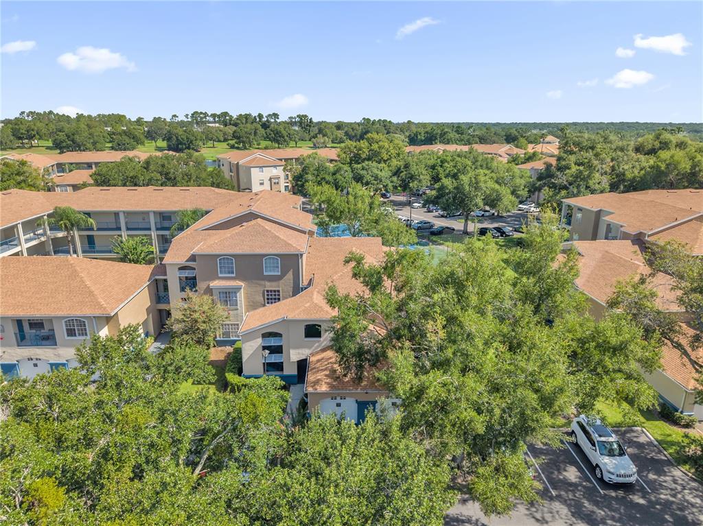 An aerial view shows multi-story apartment buildings with tan stucco walls and brown shingled roofs — 7300 WESTPOINTE BOULEVARD UNIT 717, ORLANDO, FL