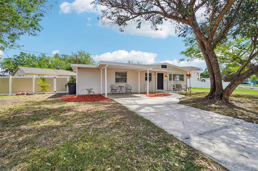 A single-story white concrete block house with a covered patio and metal outdoor furniture — 541 FIREFLY LANE, APOLLO BEACH, FL