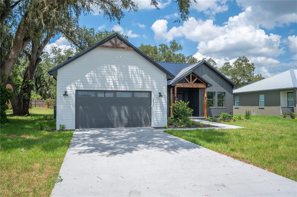 A modern single-story house with a white horizontal-sided garage and dark vertical-sided entryway — 2411 OLD MEDULLA ROAD, LAKELAND, FL