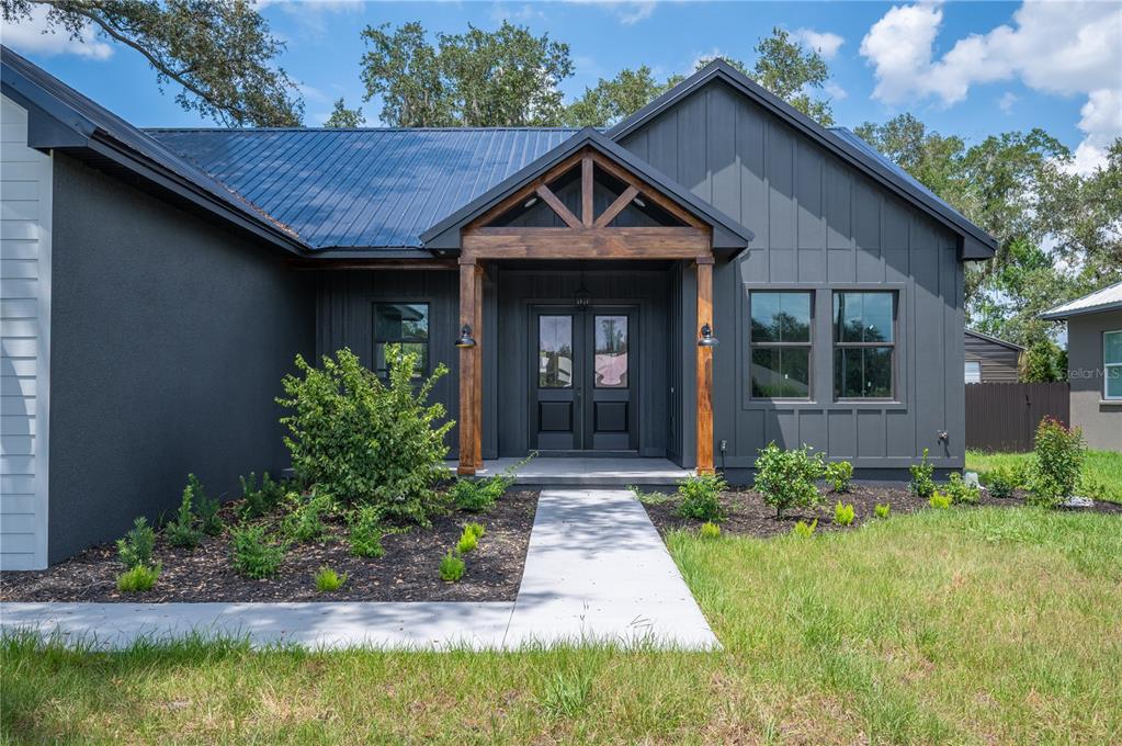 A modern dark gray house with a metal roof and a wooden front porch gable — 2411 OLD MEDULLA ROAD, LAKELAND, FL
