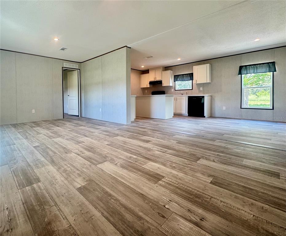 An open-concept living area features wood-look flooring, light-colored walls, and an adjacent kitchen with white cabinetry — 5135 TURTLE DOVE TRAIL, LAKELAND, FL