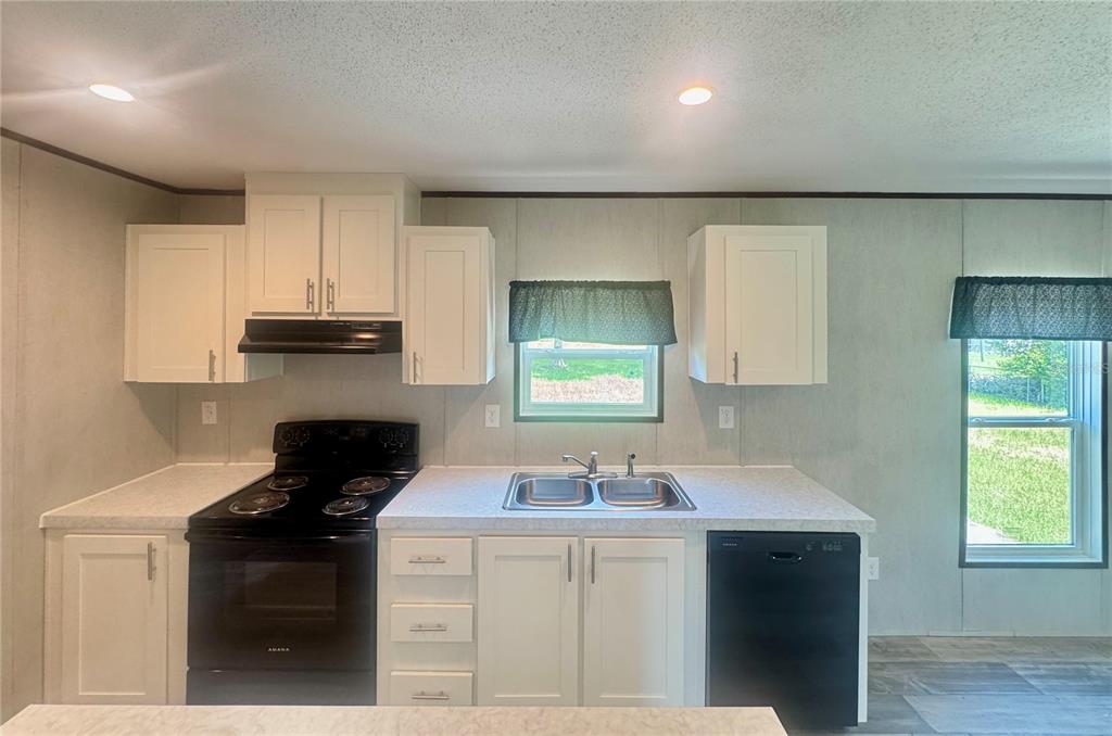 A kitchen features white cabinets, black appliances, a double-basin sink, and light-colored countertops — 5135 TURTLE DOVE TRAIL, LAKELAND, FL