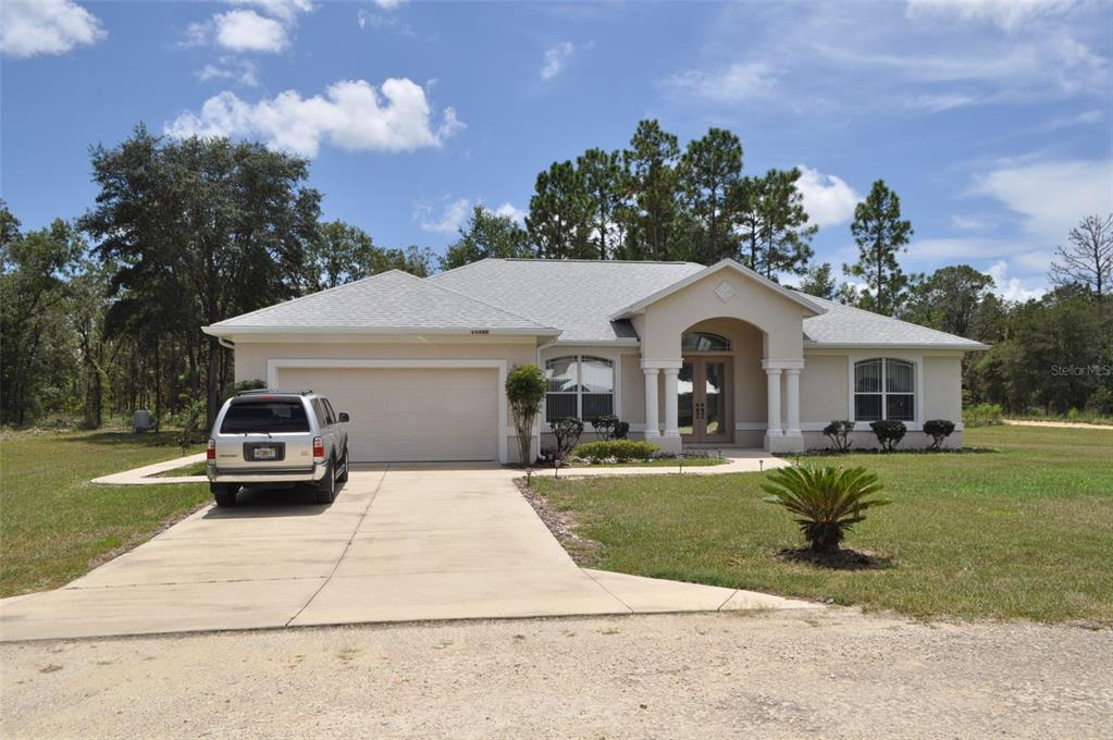 A single-story beige house with a two-car garage and a paved driveway — 15580 NE 16TH LANE, WILLISTON, FL