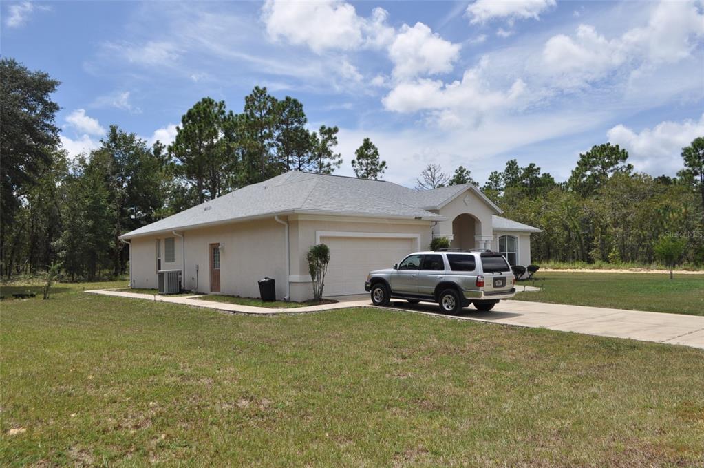 A single-story house with a beige stucco exterior, a two-car garage, and a driveway — 15580 NE 16TH LANE, WILLISTON, FL