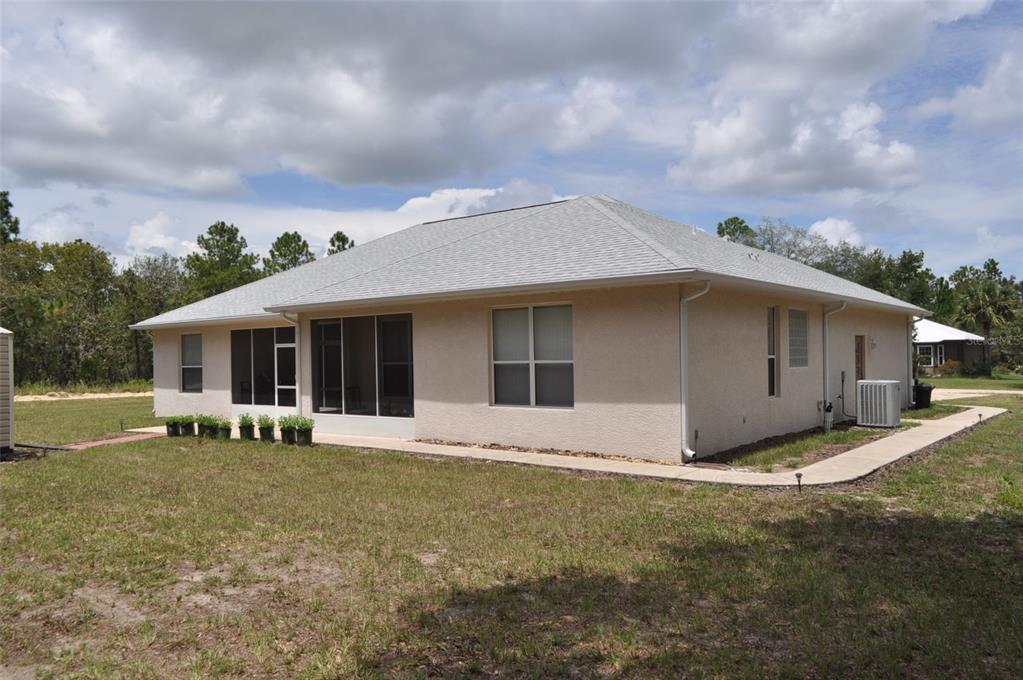 A beige stucco house with a screened-in porch and a gray shingled hip roof — 15580 NE 16TH LANE, WILLISTON, FL