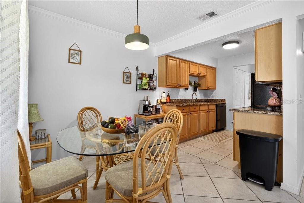 A dining area with a glass table and rattan chairs sits adjacent to a kitchen — 12 BRIGANTINE CT COURT, ST AUGUSTINE, FL