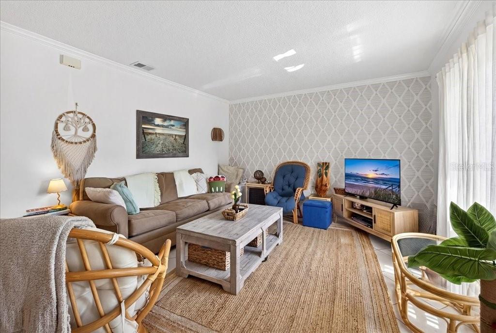 A living room features a brown sofa, a wooden coffee table, and patterned wallpaper — 12 BRIGANTINE CT COURT, ST AUGUSTINE, FL