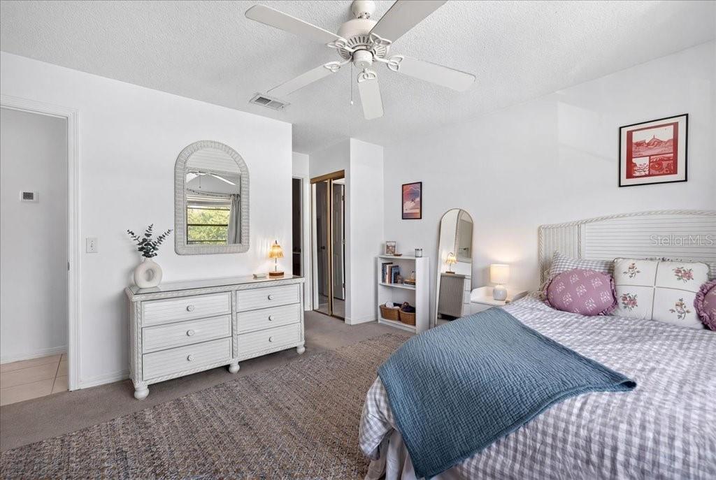 A bedroom features a white dresser, a bed with patterned pillows, and a ceiling fan — 12 BRIGANTINE CT COURT, ST AUGUSTINE, FL
