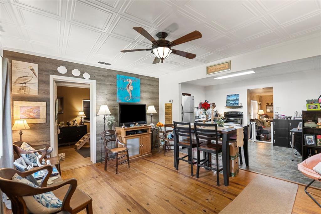 A living room with wood floors, a coffered ceiling, and a dining area in the background — 8709 EL PORTAL DRIVE, TAMPA, FL