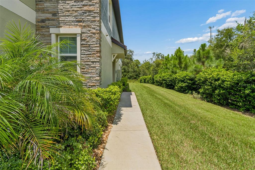 A concrete walkway runs along the side of a house with stone and stucco siding — 11166 WISHING CLOUD ROAD, LAND O LAKES, FL