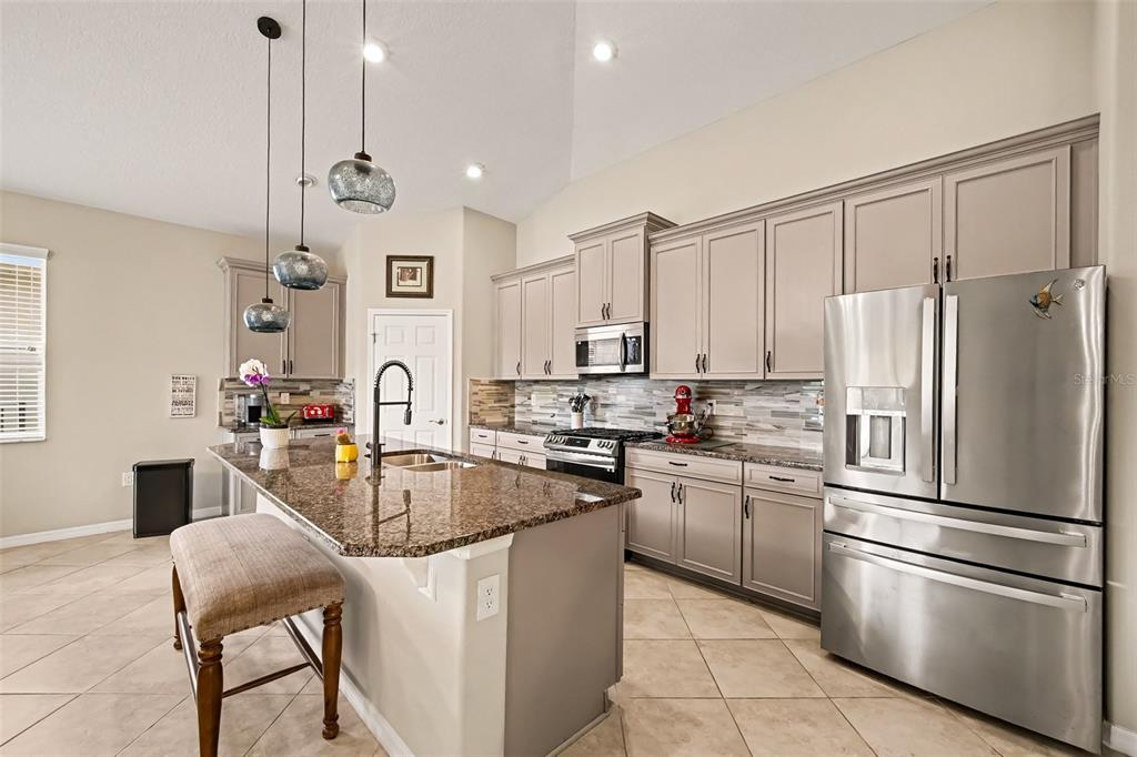 A spacious living and dining area features vaulted ceilings, tile flooring, and a leather sectional — 43 LAGOON WAY, PALM COAST, FL