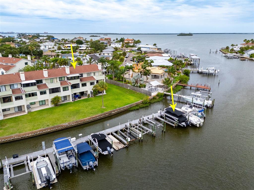 An aerial view shows a multi-story waterfront condominium building with a private boat dock — 2395 HANOVER DR, DUNEDIN, FL