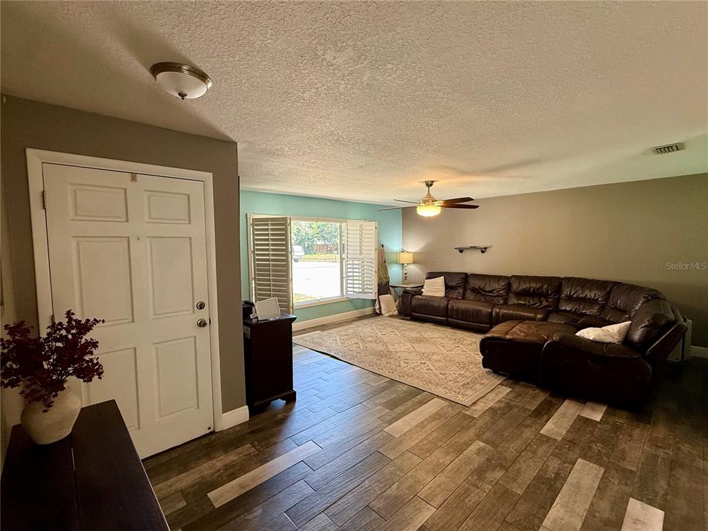 A living room features wood-look tile flooring, a large brown sectional sofa, and a ceiling fan — 2522 SUWANNEE DRIVE, COCOA, FL