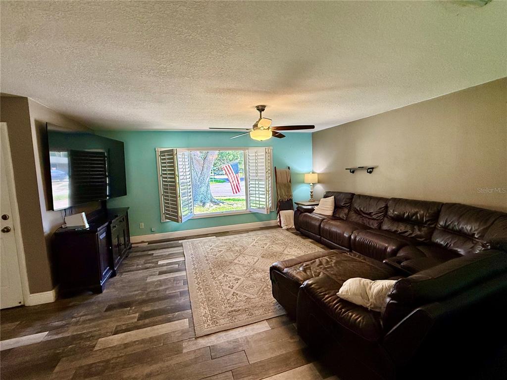 A living room features a large brown sectional, a patterned rug, and a teal accent wall — 2522 SUWANNEE DRIVE, COCOA, FL