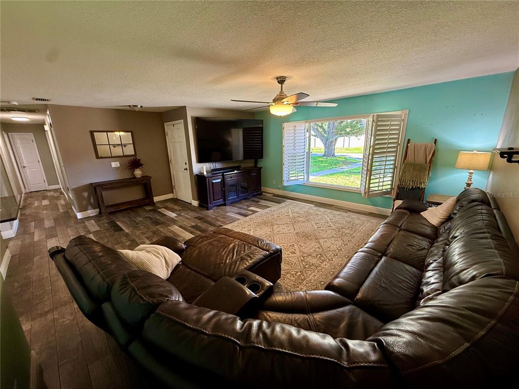 A living room features a large brown sectional sofa, a television, and a ceiling fan — 2522 SUWANNEE DRIVE, COCOA, FL