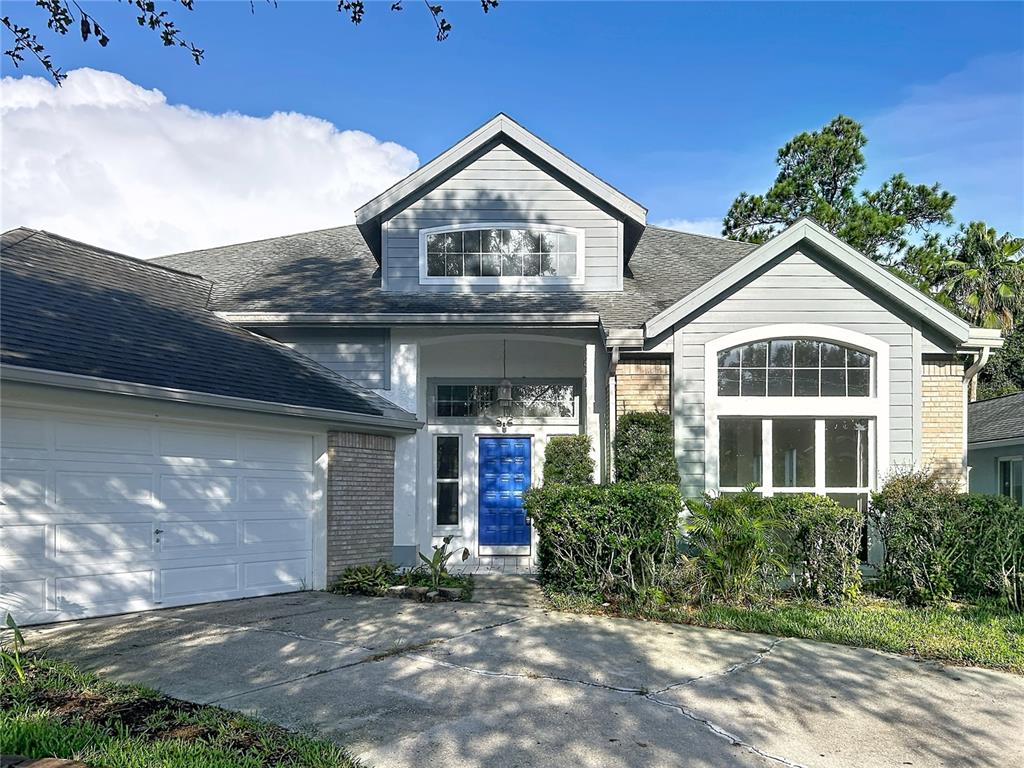 A two-story house with gray siding, a blue front door, and a concrete driveway — 9122 ROCKROSE DRIVE, TAMPA, FL