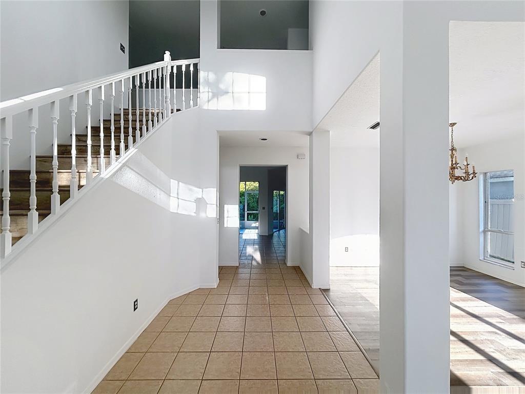 A tiled entryway features a white staircase with a wooden railing and a view beyond — 9122 ROCKROSE DRIVE, TAMPA, FL