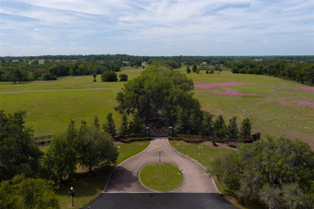 An aerial view shows a gated entrance with a circular driveway leading to a tree-lined path — TBD SE 111TH PLACE, OCALA, FL