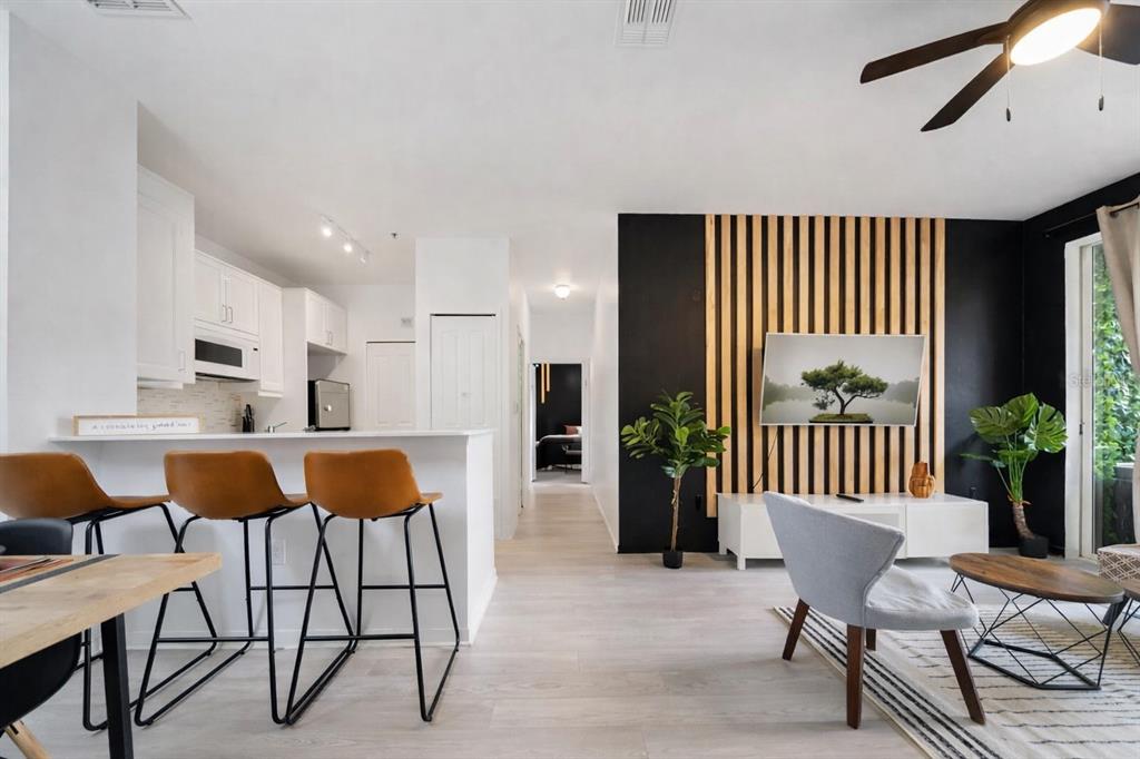 An open-concept living area features a kitchen with bar seating and a wood-slatted accent wall — 8824 DUNES COURT COURT UNIT 103, KISSIMMEE, FL