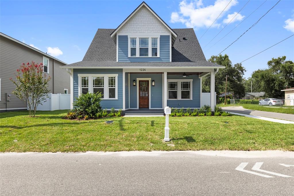 A blue two-story house with a front porch, white trim, and a shingled roof — 1224 E CHELSEA STREET, TAMPA, FL