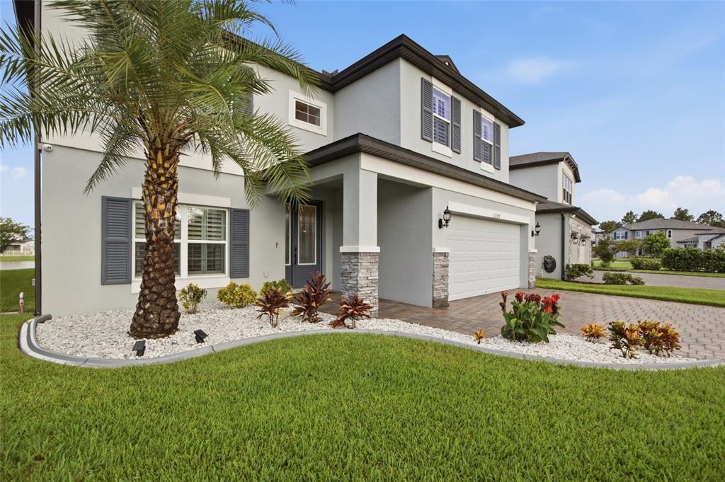 A two-story house with a palm tree, stone accents, and a paved driveway — 22319 WOODMEN HALL DRIVE, LAND O LAKES, FL