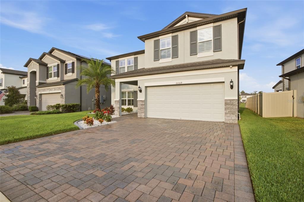 A two-story suburban house with a paved driveway, a two-car garage, and a palm tree — 22319 WOODMEN HALL DRIVE, LAND O LAKES, FL