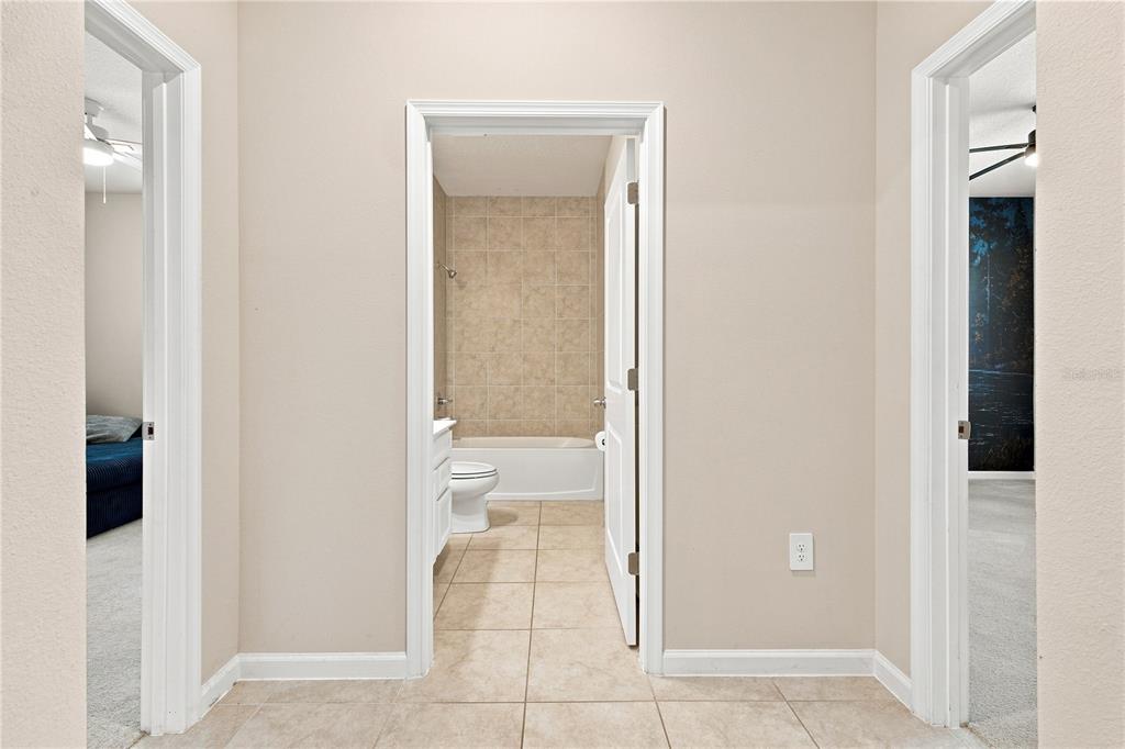 A hallway with beige walls leads to a bathroom with a tub and tiled floor — 3754 ISLE ROYAL PLACE, APOPKA, FL