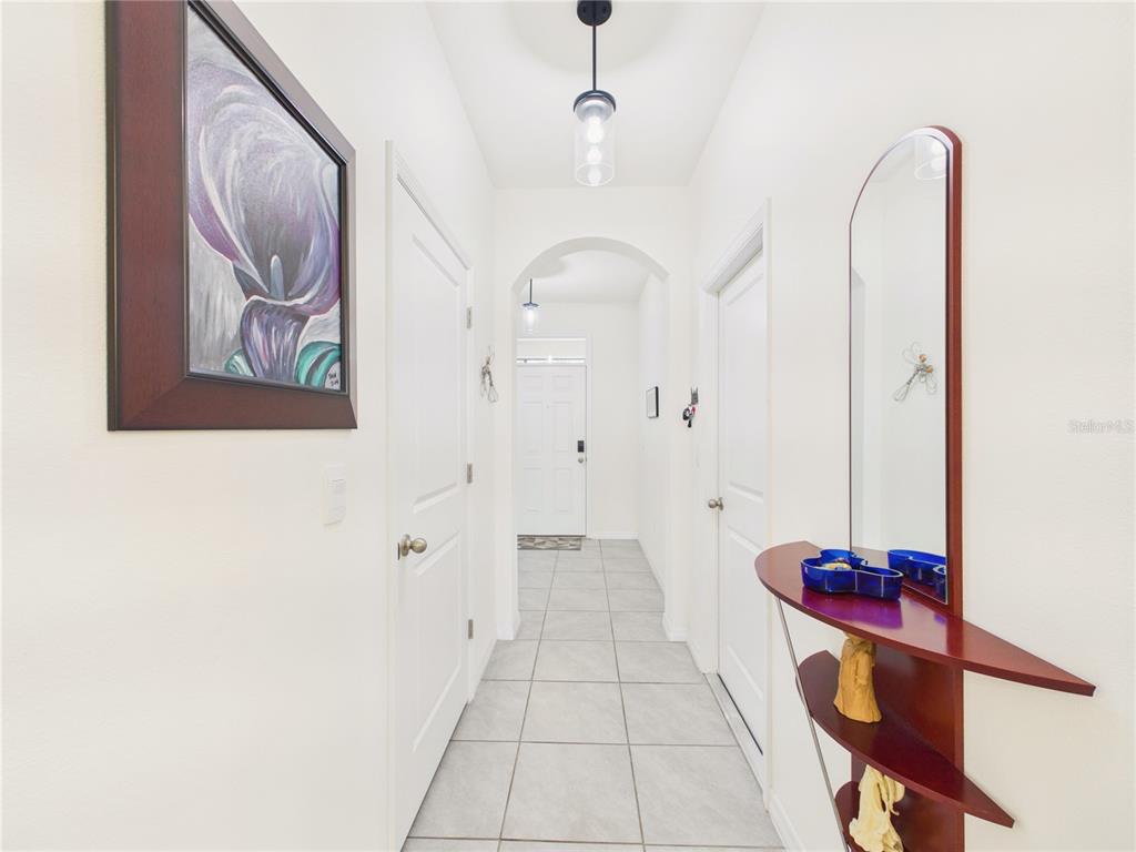 A hallway with white walls, tile flooring, two closed doors, and a wall-mounted mirror shelf — 5262 DRAGONFLY DRIVE, WILDWOOD, FL