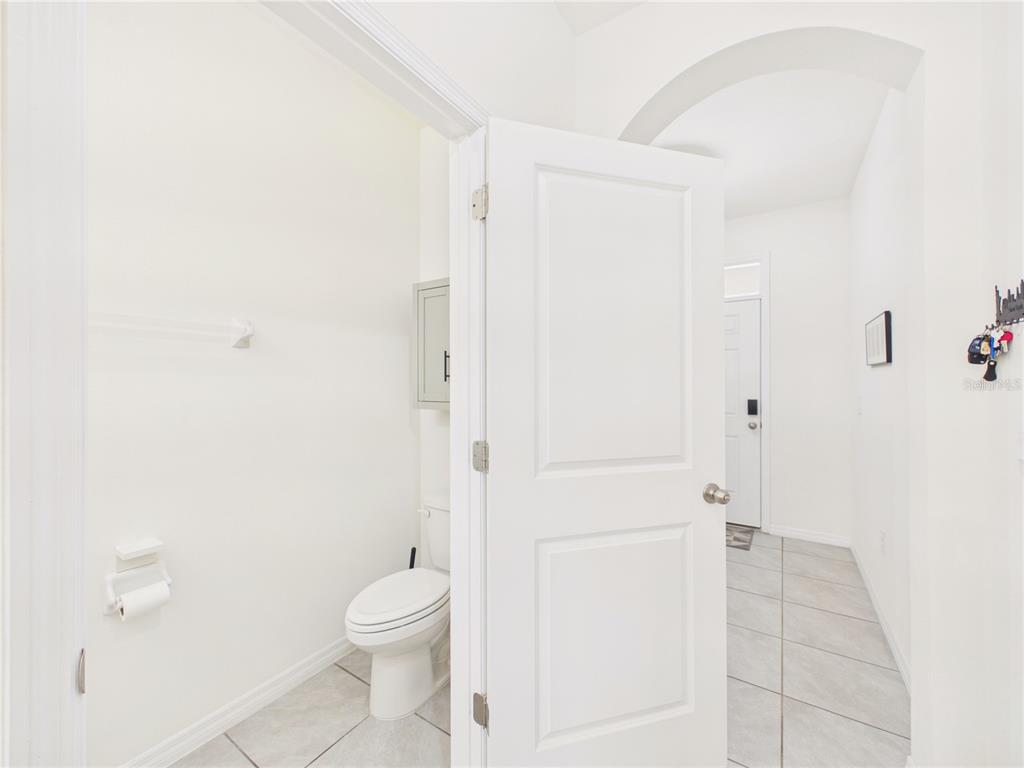 A half bathroom with a white toilet and tile flooring is visible through an open door — 5262 DRAGONFLY DRIVE, WILDWOOD, FL