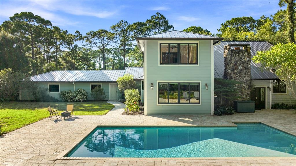 A two-story house with light green siding, a metal roof, and a backyard swimming pool — 6950 EL DORADO DRIVE, SARASOTA, FL