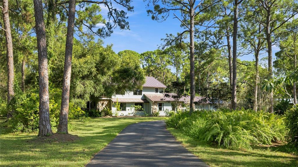 A two-story house with a metal roof and stone accents sits at the end of a driveway — 6950 EL DORADO DRIVE, SARASOTA, FL