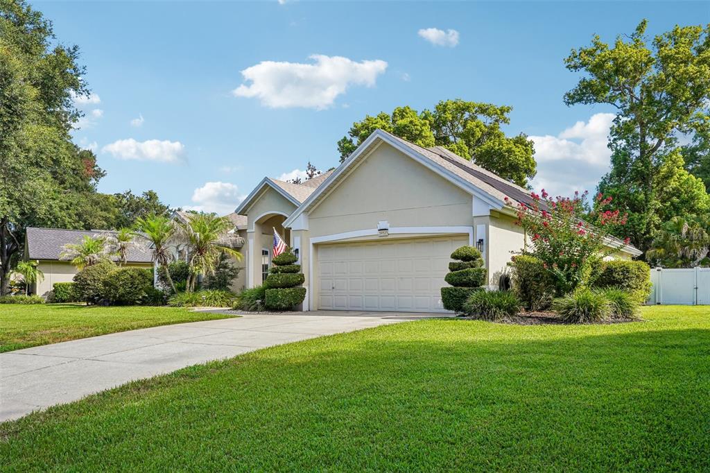 A single-story house with a beige stucco exterior, a two-car garage, and a manicured lawn — 19323 PARK PLACE BOULEVARD, EUSTIS, FL
