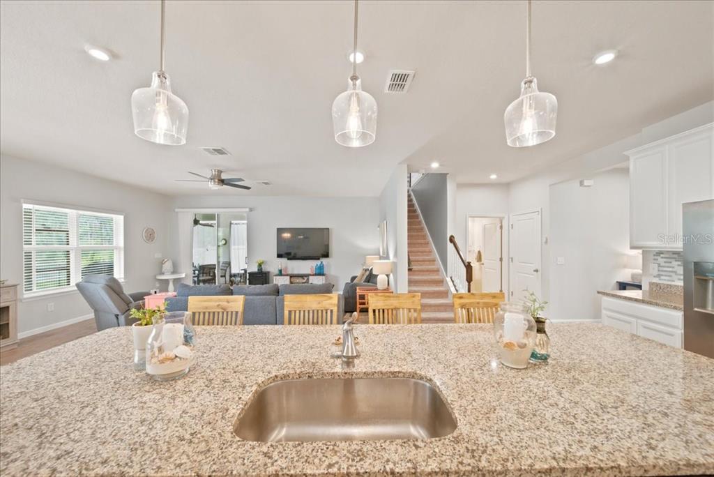 A kitchen island with a granite countertop and sink overlooks an open-concept living area — 11432 64TH STREET E, PARRISH, FL