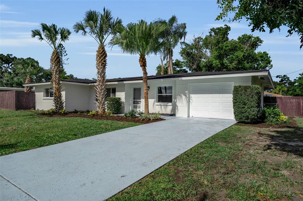 A single-story house with a white exterior, a concrete driveway, and several palm trees — 2769 WISTERIA PLACE, SARASOTA, FL