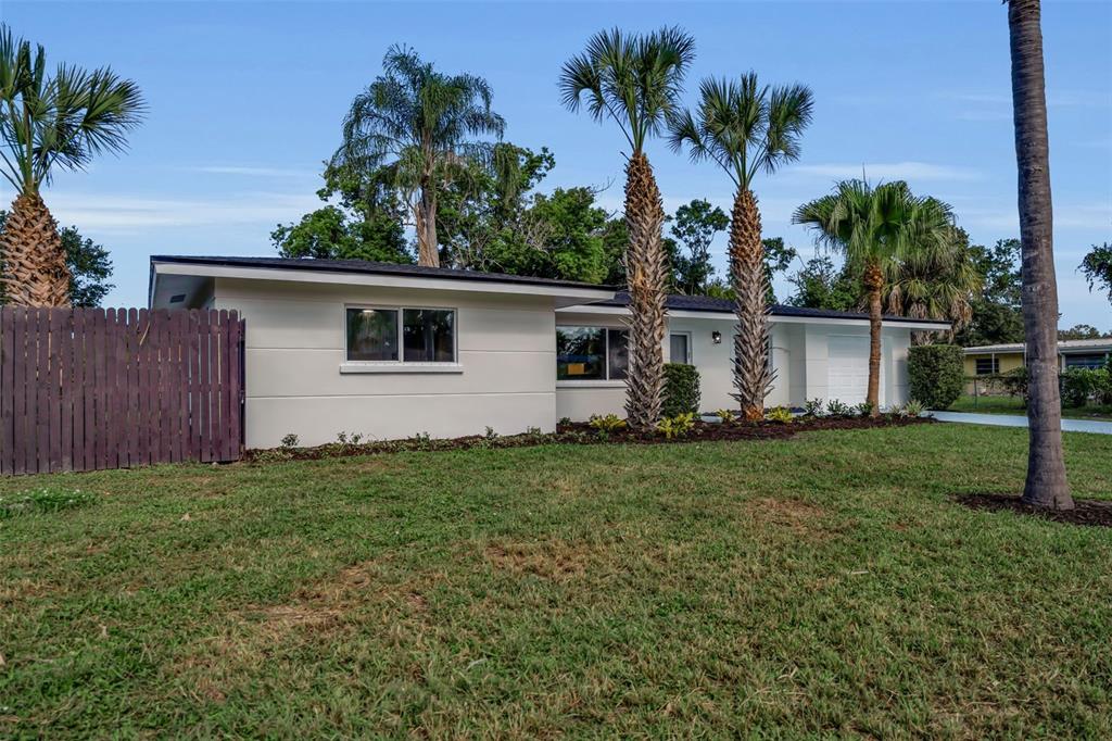A single-story house with a white exterior, palm trees, and a wooden fence — 2769 WISTERIA PLACE, SARASOTA, FL