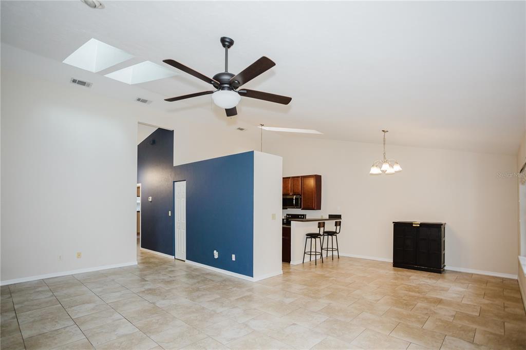 An open-concept living and dining area features tile flooring, a blue accent wall, and skylights — 3915 NW 7TH PLACE, GAINESVILLE, FL