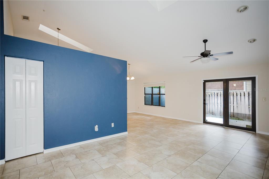 A living room with beige tile floors, a blue accent wall, and glass patio doors — 3915 NW 7TH PLACE, GAINESVILLE, FL