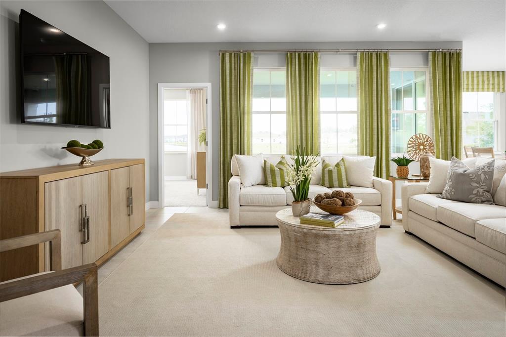 A living room features two beige sofas, a round coffee table, and green striped curtains — 20017 GOLDEN GLOW LOOP, VENICE, FL
